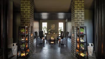 A reception area with a reception desk, two chairs, a coffee table, and two shelving units with plants.