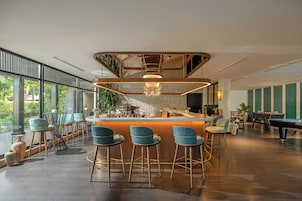 A modern bar area with a curved counter, bar stools, and a pool table.