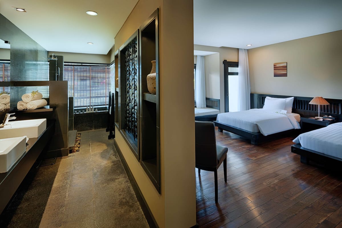 A hotel room with a bathroom, a bed, a chair, and a bedside table.