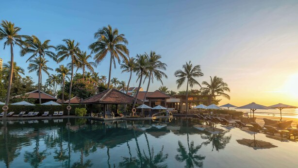 A resort pool with palm trees and umbrellas, surrounded by lounge chairs and a beach view. - Anantara Mui Ne Resort (Mui Ne)