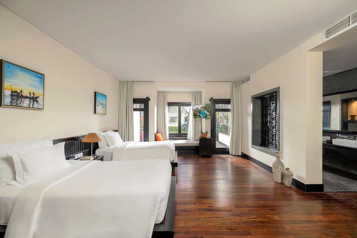 A hotel room with two beds, a large window, and a view of the outdoors.