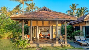 A covered outdoor seating area with a pool, surrounded by palm trees and greenery. - Anantara Mui Ne Resort (Mui Ne)