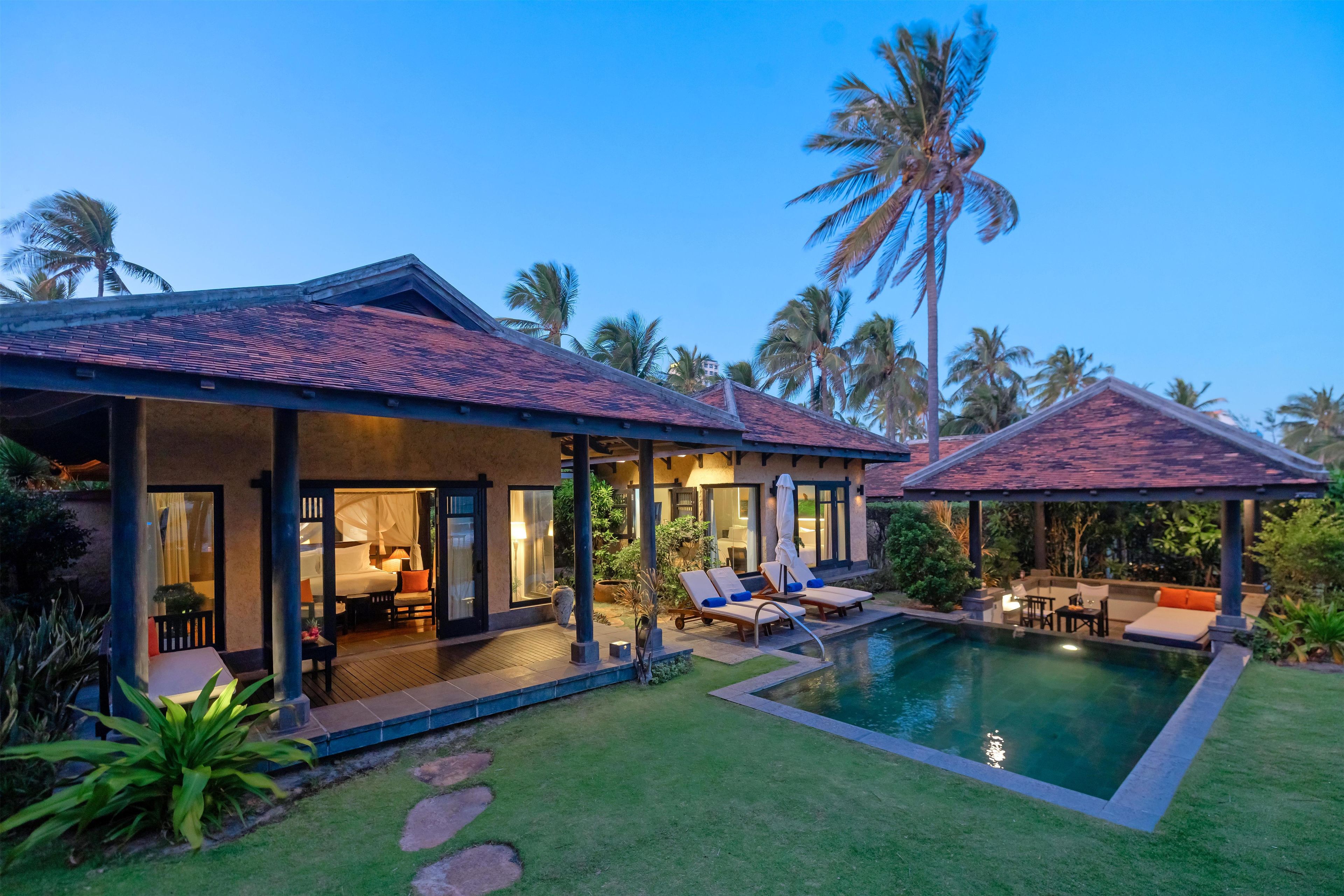 Una villa moderna con piscina, mobiliario exterior y exuberante vegetación tropical.