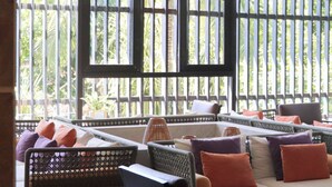 A sunlit outdoor seating area with wicker furniture, cushions, and a potted plant. - Anantara Mui Ne Resort (Mui Ne)