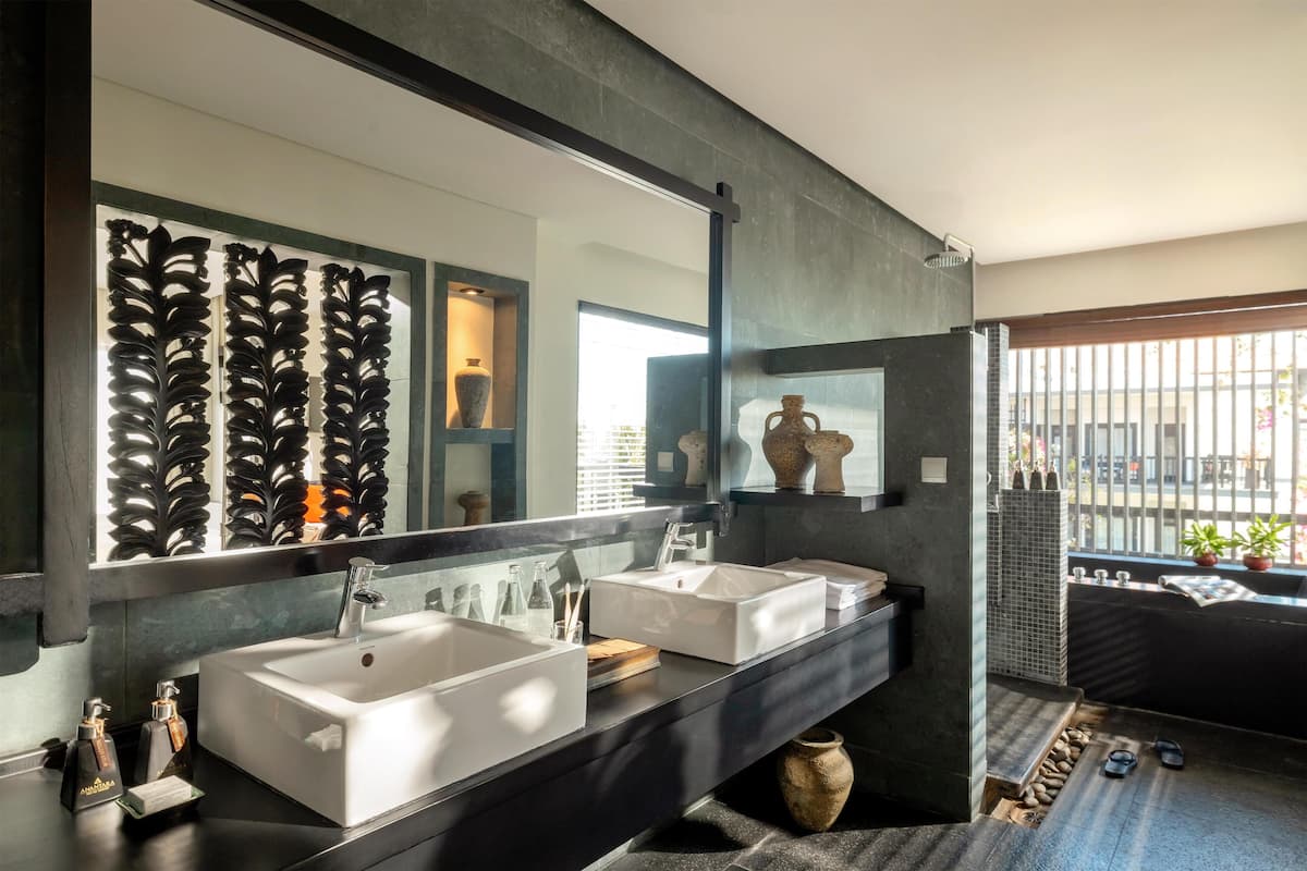 A modern bathroom with two sinks, a large mirror, and a view of the city through a window.