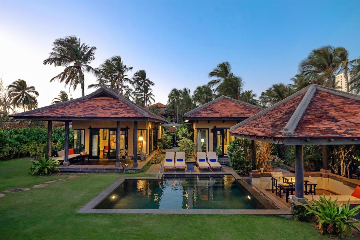A resort with a swimming pool, lounge chairs, and palm trees.