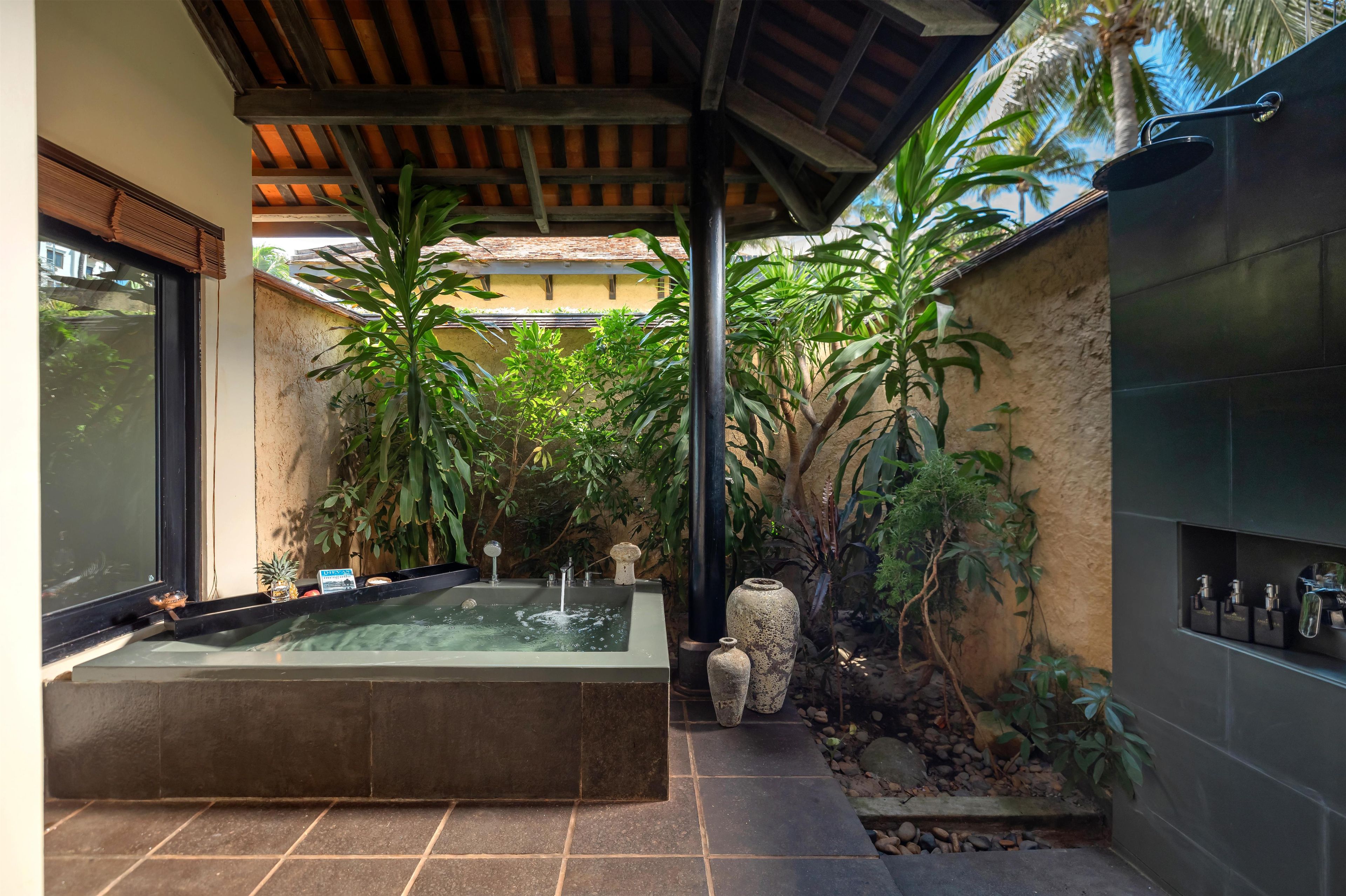 A spa area with a hot tub, surrounded by tropical plants and a stone wall.