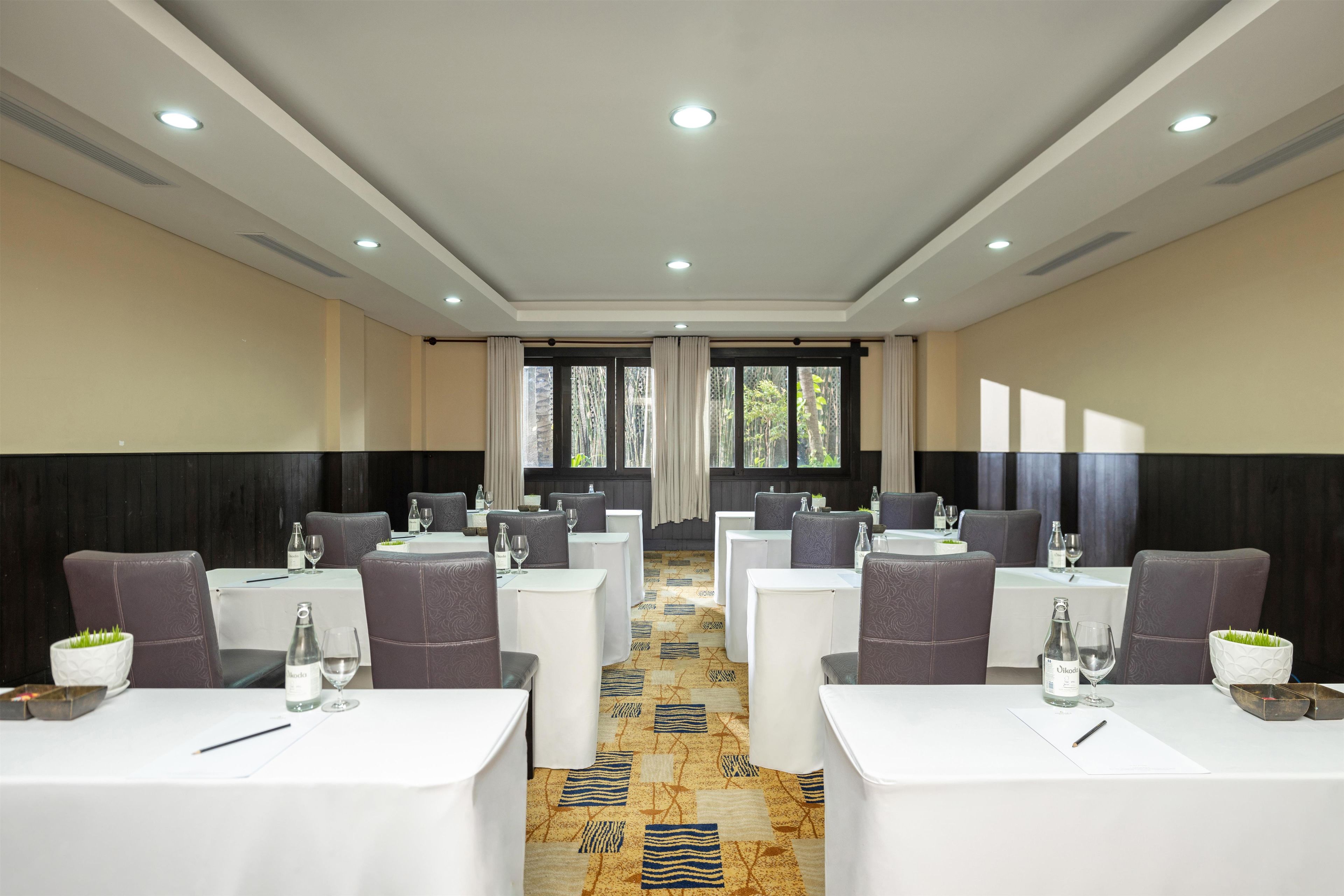 A conference room with tables and chairs, large windows, and a patterned carpet.