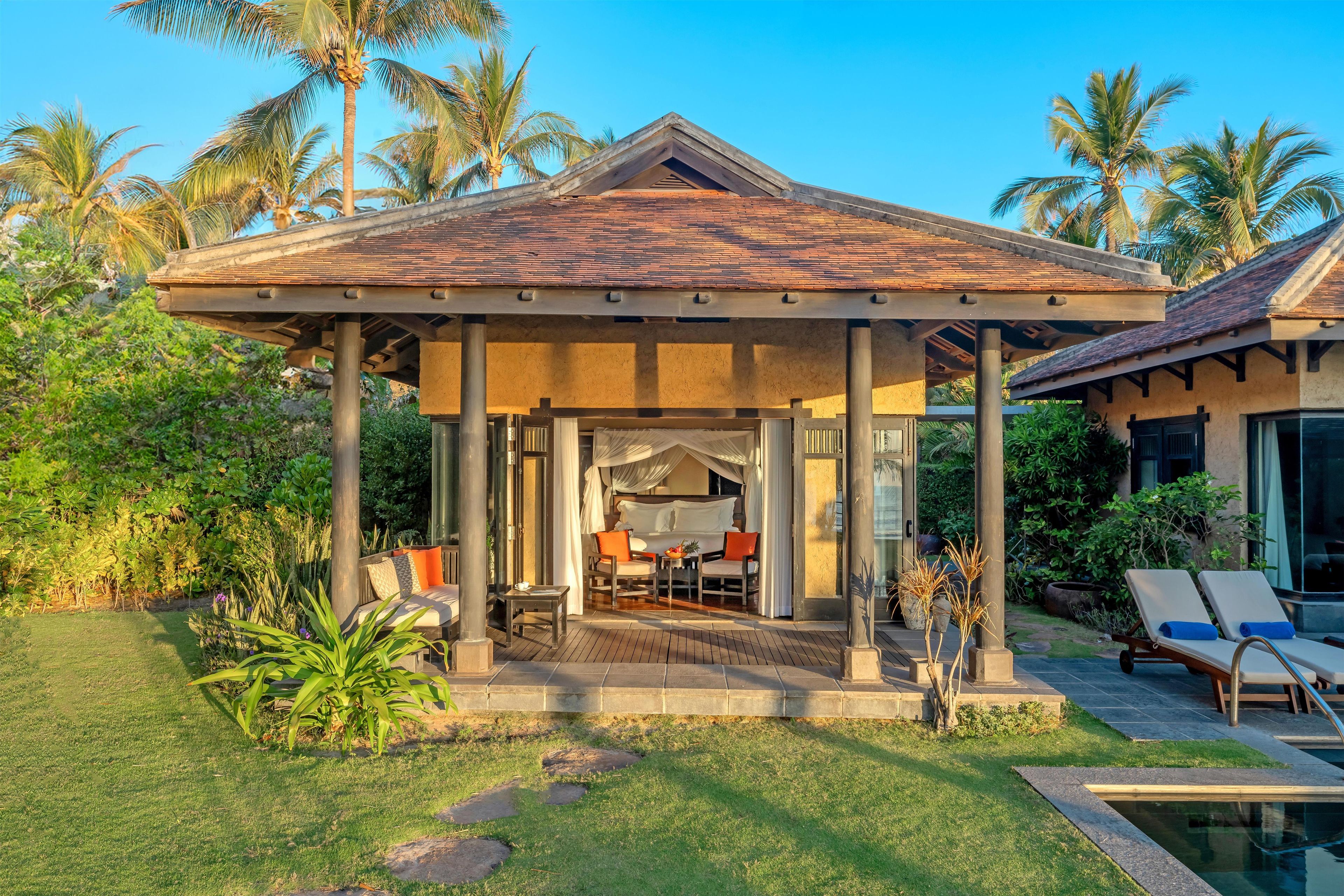 A covered outdoor seating area with a pool and lounge chairs.