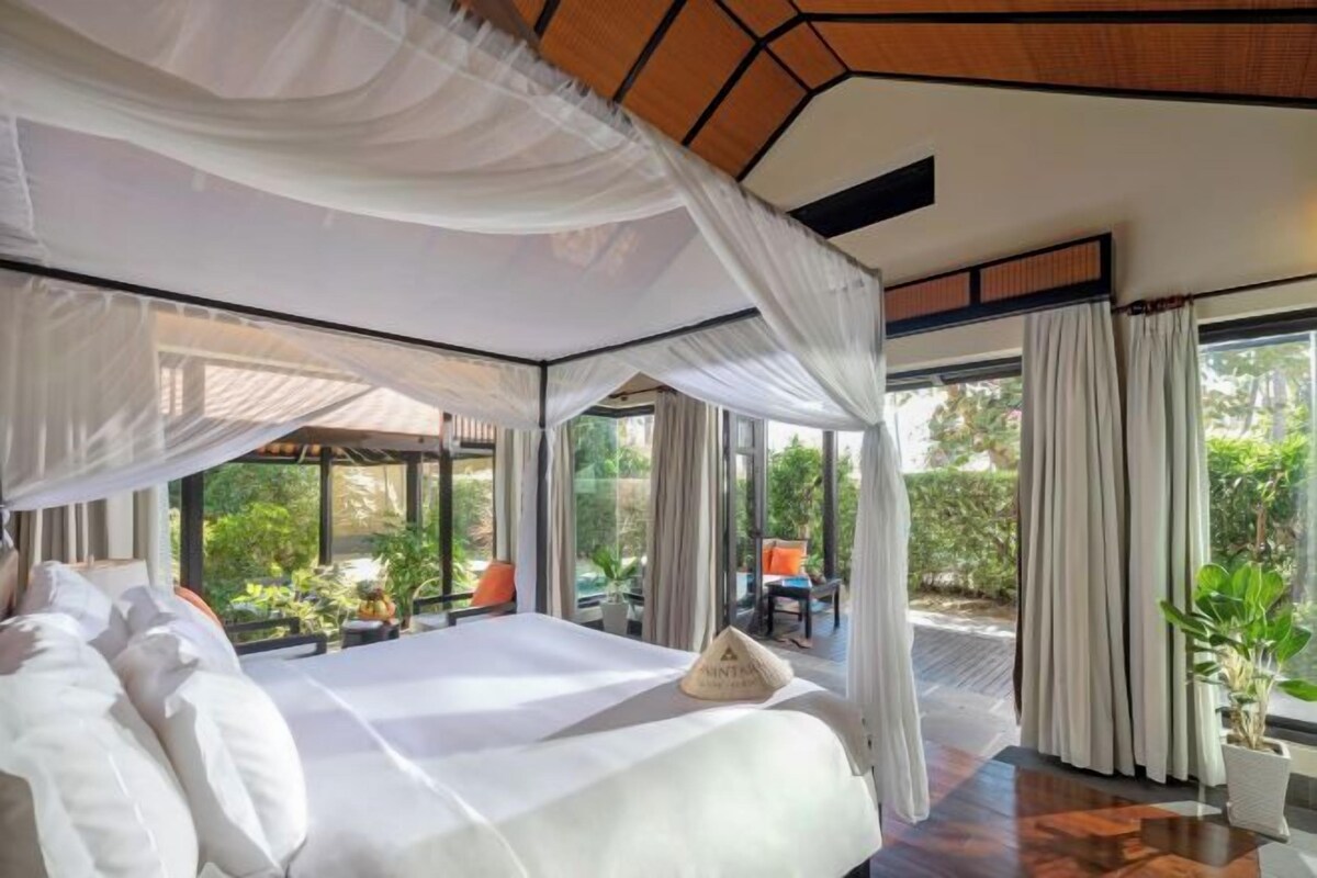 Un dormitorio con cama con dosel, ventanas amplias y vistas al exterior.
