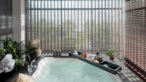 A modern spa with a hot tub, surrounded by large windows with blinds, and a stone sculpture on the side. - Anantara Mui Ne Resort (Mui Ne)