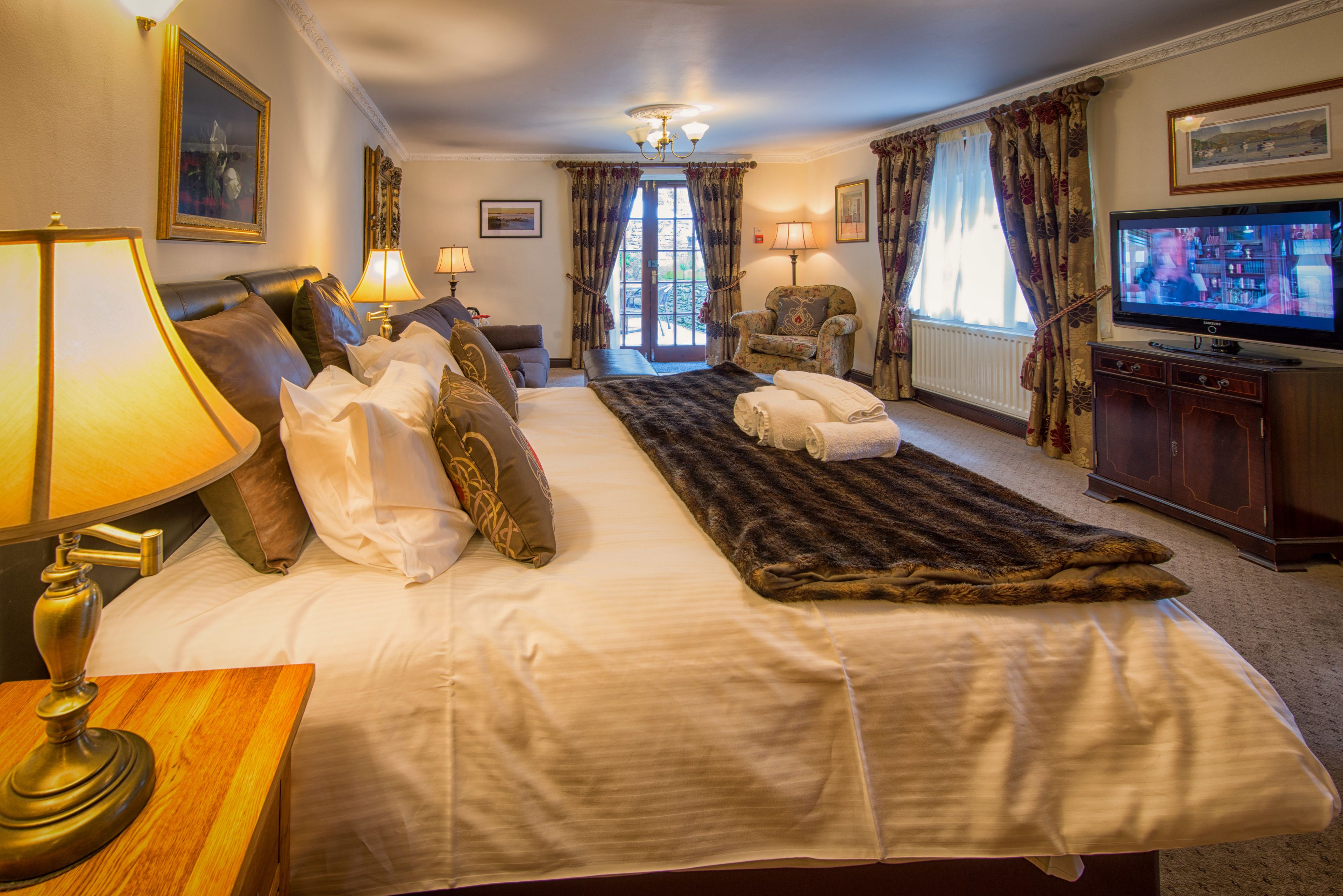 Une chambre d’hôtel avec un grand lit, une télévision, une chaise et une vue sur l’extérieur par la fenêtre.