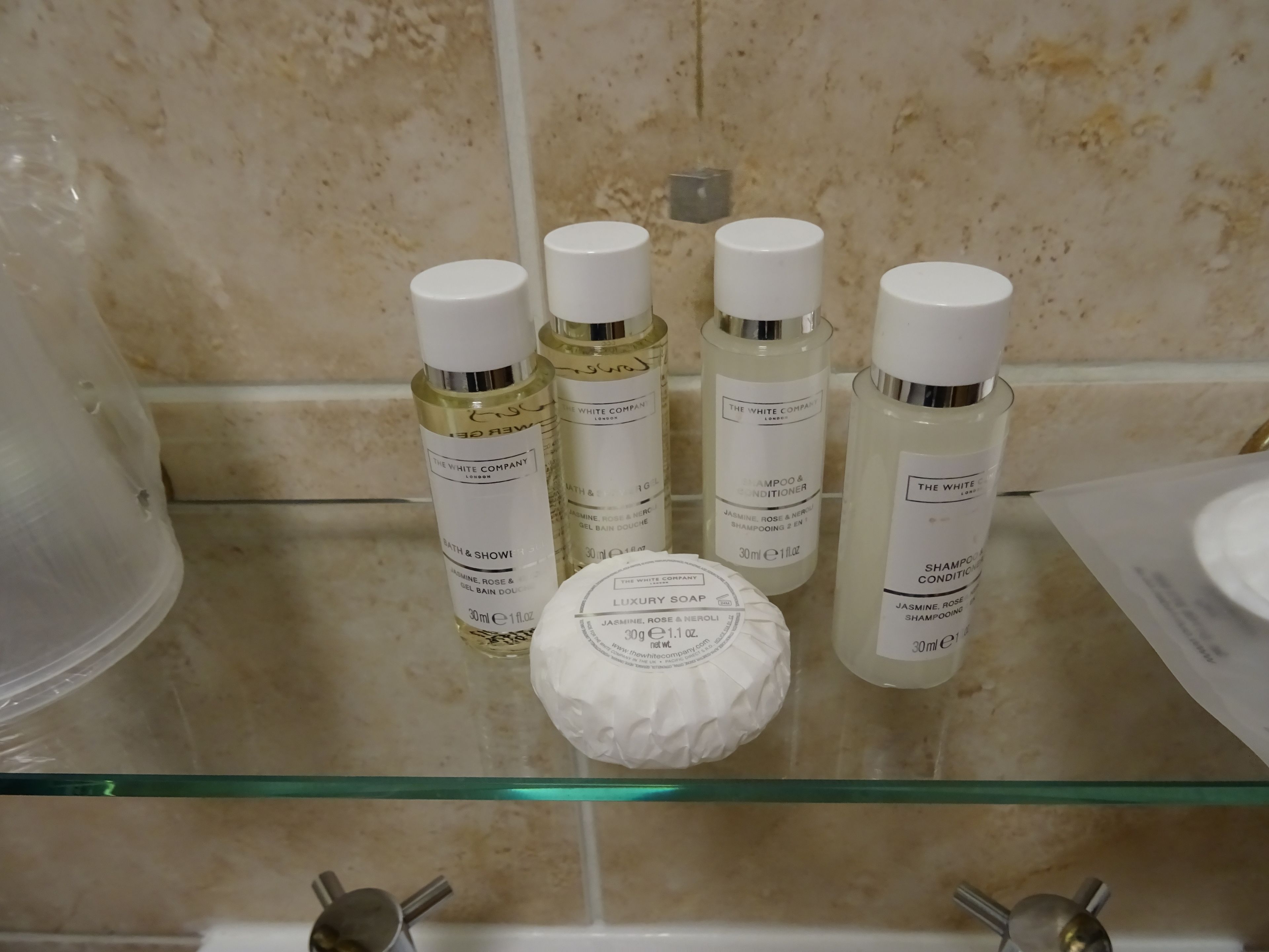 Een badkamerplank met vier flessen The White Company badproducten en een stuk Luxury Soap.