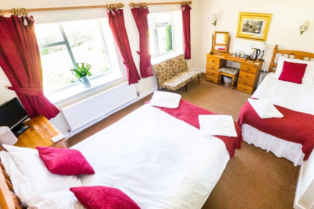 A hotel room with two beds, a desk, a chair, and a window with curtains.