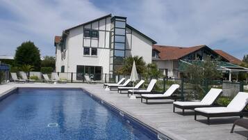 A swimming pool with lounge chairs and a building with large windows in the background.