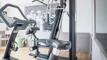 Un gimnasio con equipo de ejercicio, un otomano verde y un cartel en la pared.