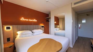 Une chambre d’hôtel moderne avec un grand lit, une tête de lit en bois et un néon mural.