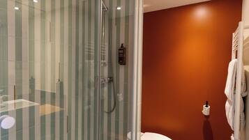 Un baño moderno con ducha de vidrio, inodoro y toallero.
