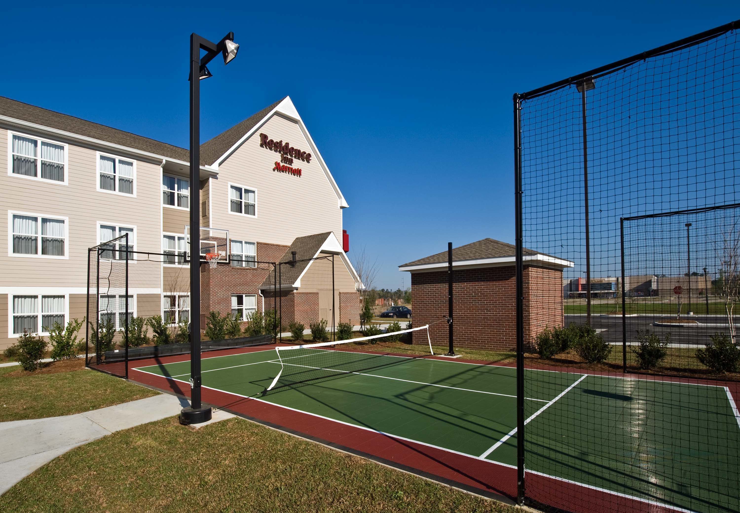 A tennis court with a net, surrounded by a fence, and a building labeled "Residence Inn".