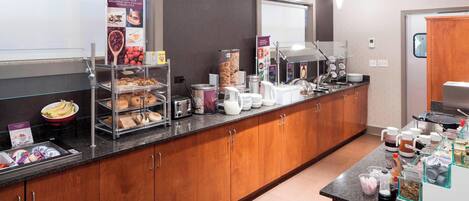 Una barra de desayuno con diferentes opciones de comida y una estación de café.
