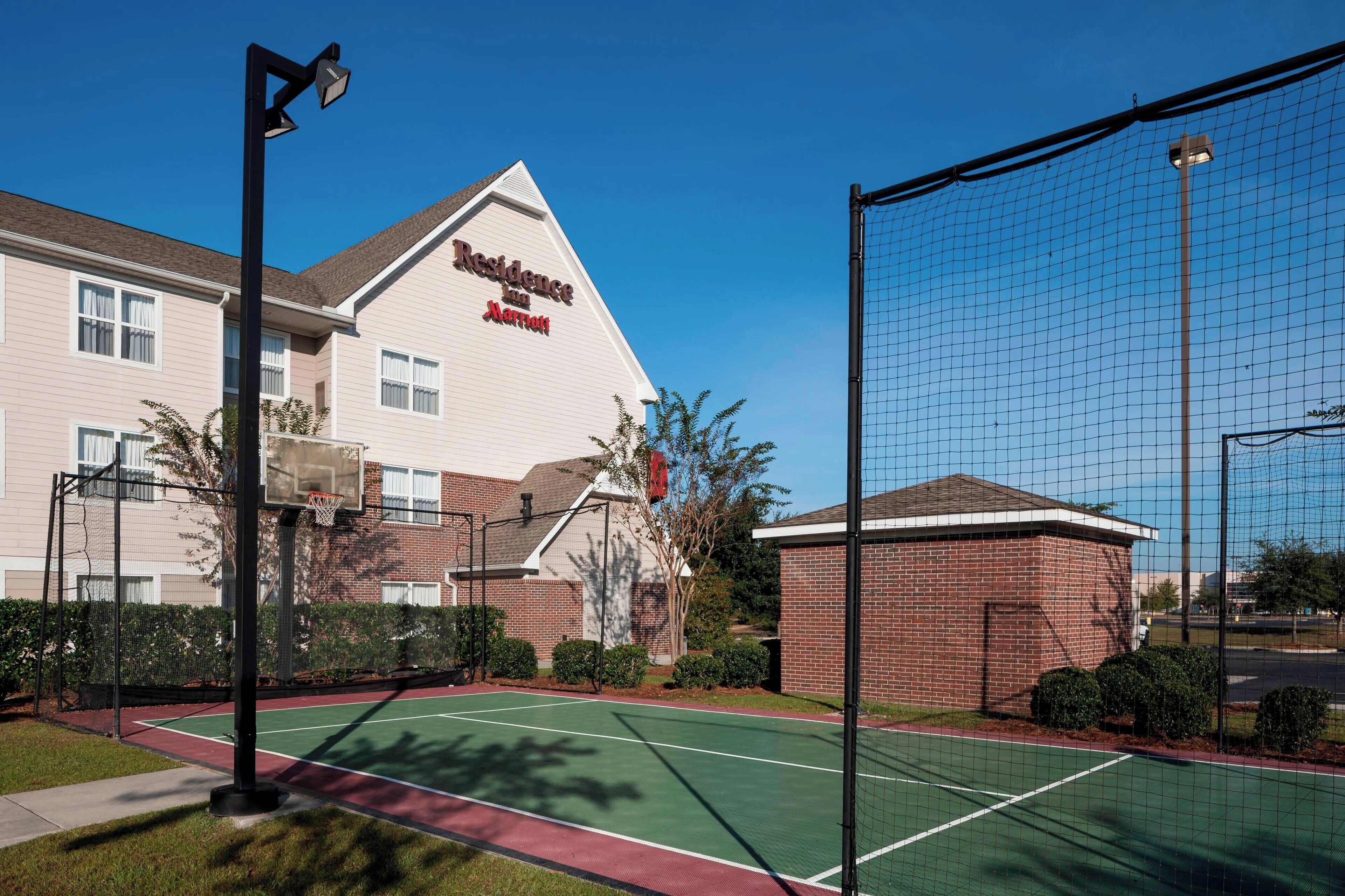 A tennis court with a net, surrounded by a fence, and a building labeled "Residence Inn Marriott" in the background.