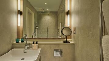 A bathroom with a sink, mirror, towel rack, and shower.
