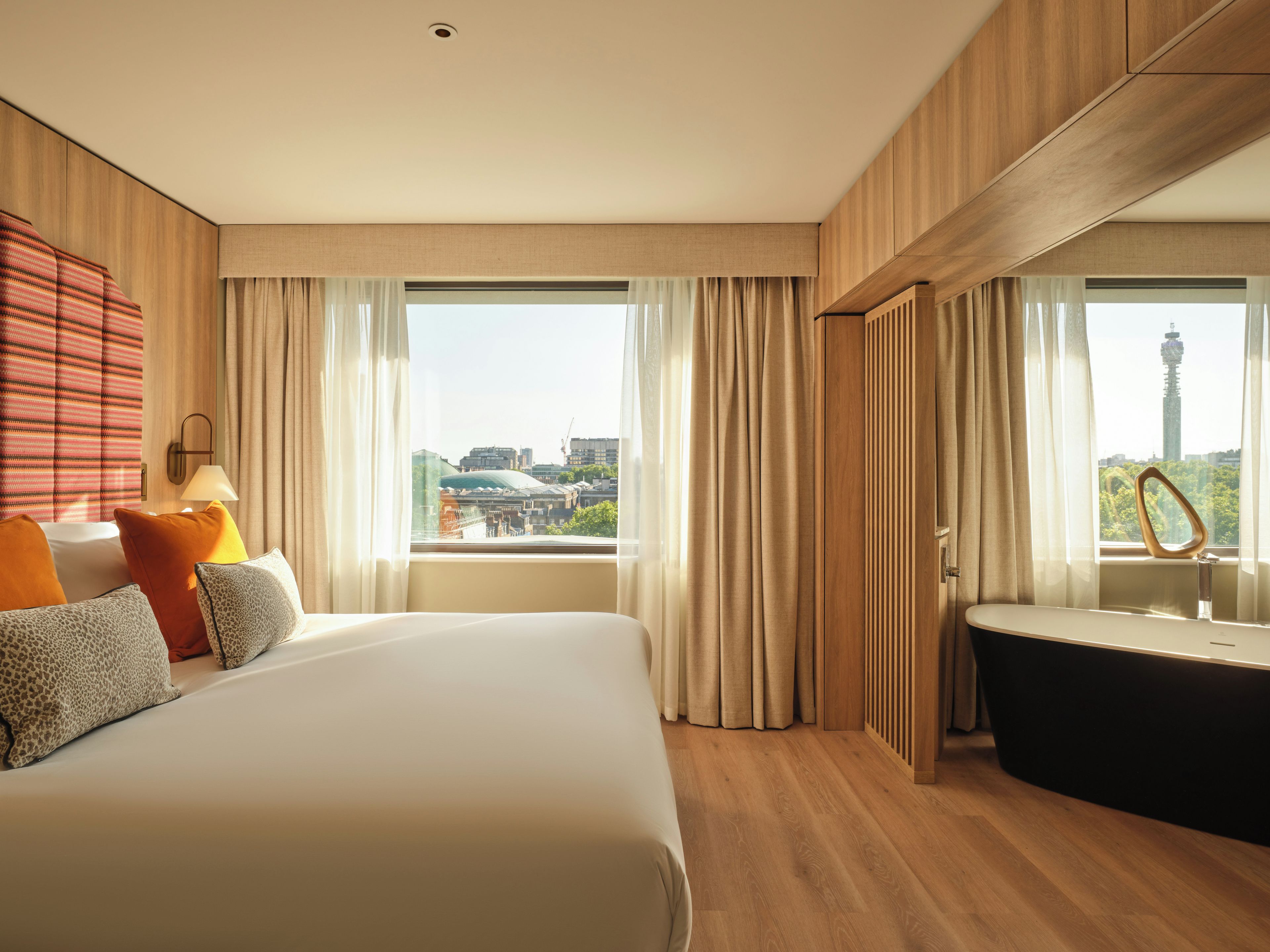 Habitación de hotel con una cama grande, una bañera y vistas a la ciudad.