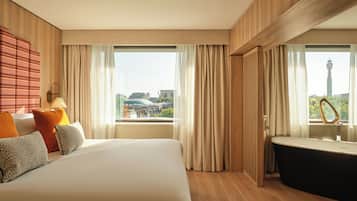 Habitación de hotel con una cama grande, una bañera y vistas a la ciudad.