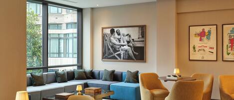 Une chambre d’hôtel moderne équipée d’un canapé, de fauteuils, d’une table basse et d’un coin lecture avec un livre.