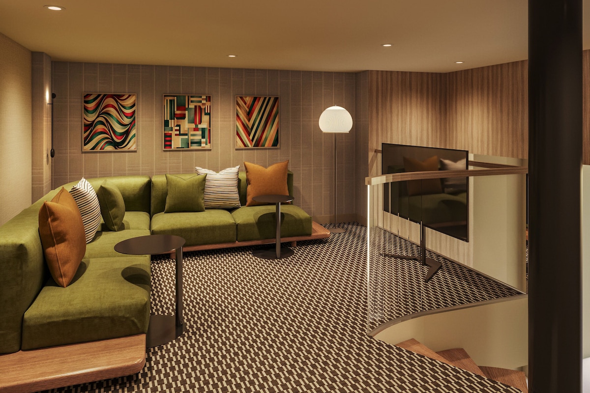 A modern living room with a green sofa, patterned carpet, and abstract wall art.
