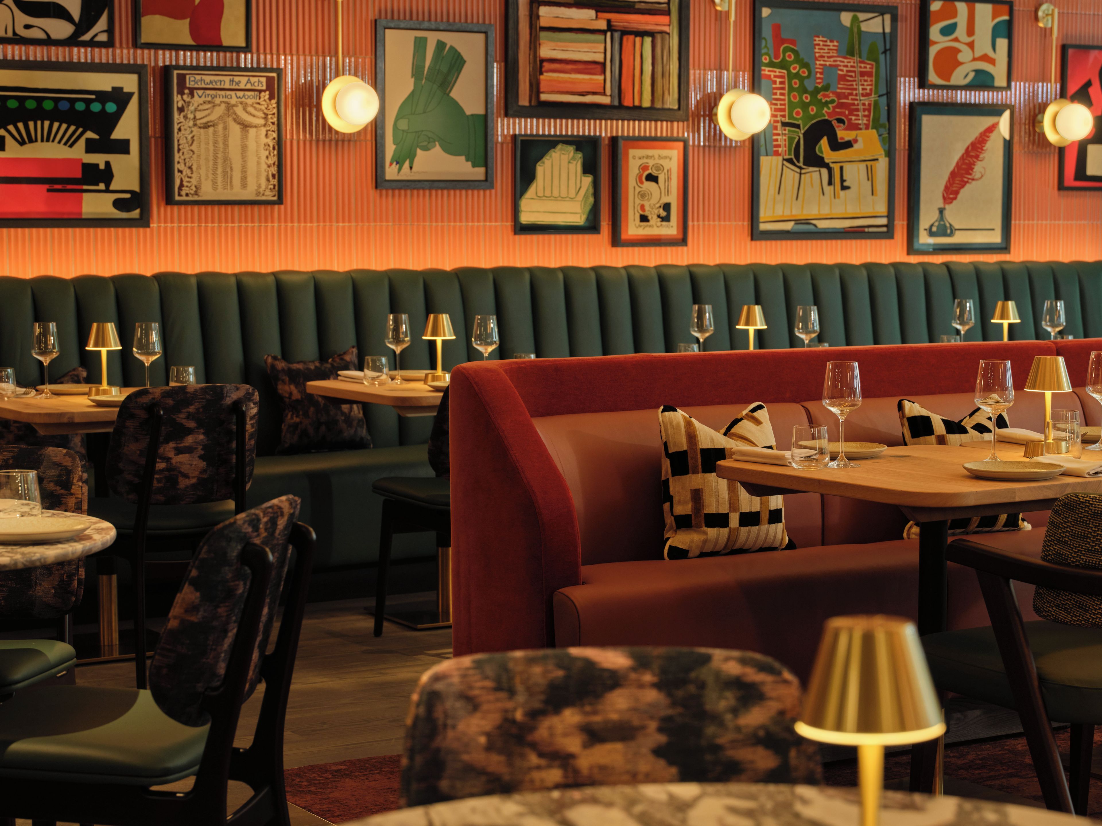 A restaurant interior with booths, tables, and chairs, featuring artwork on the walls and a warm ambiance.