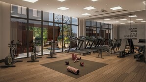 A modern gym with treadmills, weights, and a view of greenery outside. - The Imperial (London)