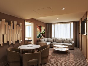 Ein modernes Hotelzimmer mit Ecksofa, rundem Couchtisch, Essbereich mit Stühlen, großem abstrakten Gemälde und Wand-Fernseher.