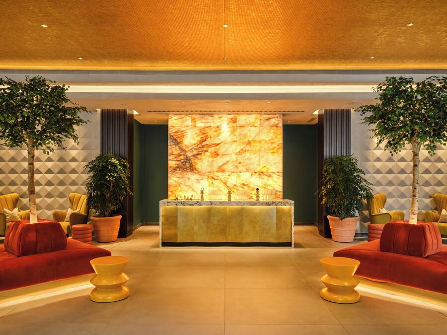 A lobby with a reception desk, two sofas, and potted plants.