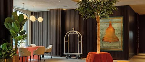 A modern interior with a red sofa, potted plants, a dining area, and a wall-mounted artwork.