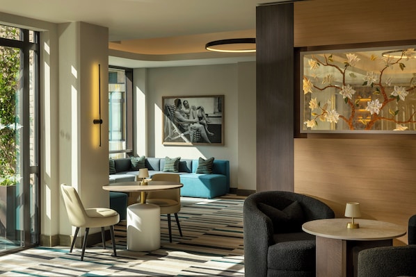 A modern hotel lobby with a seating area, a dining table, and a large window. - The Imperial (London)