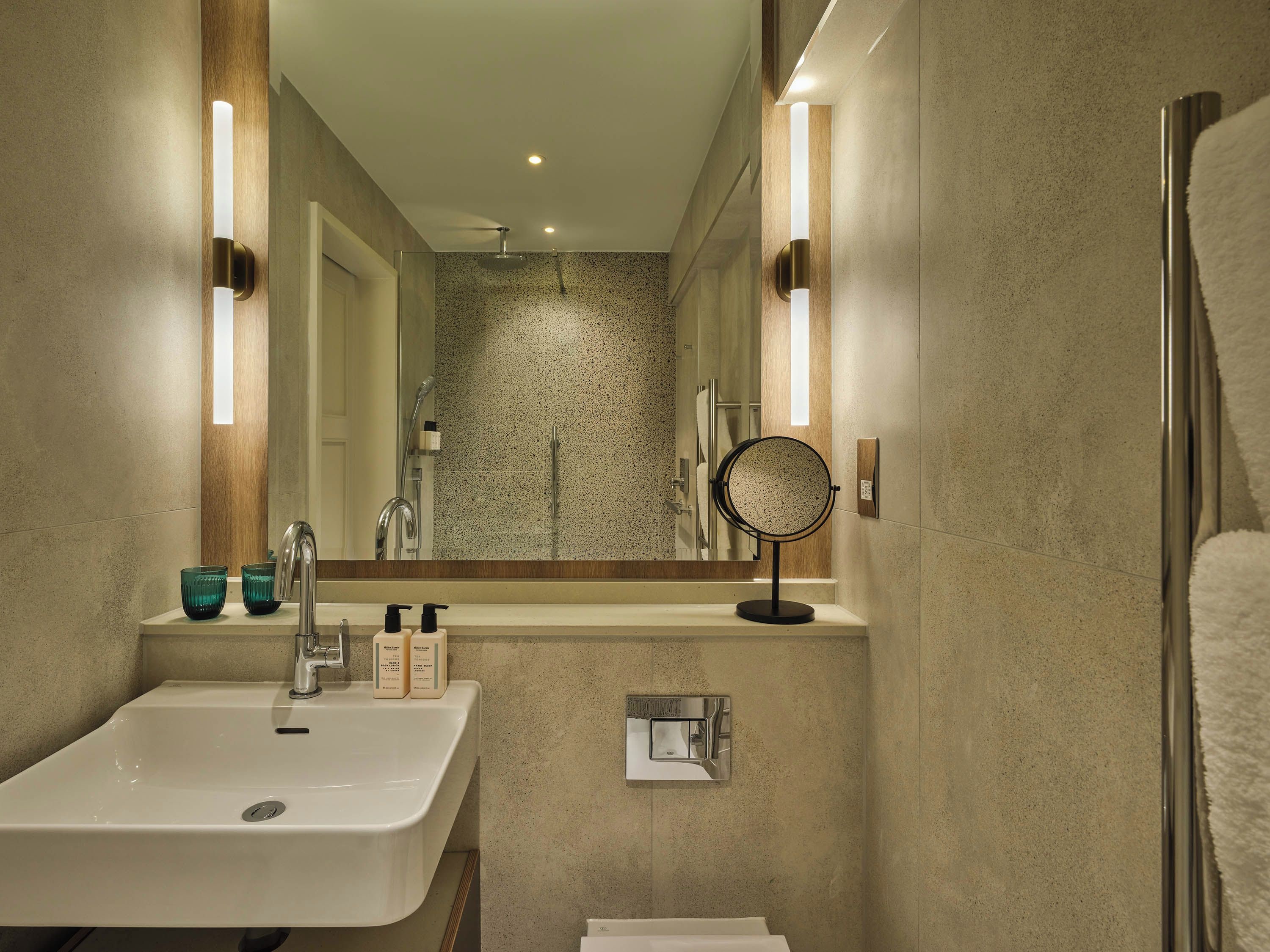 A modern bathroom with a large mirror, a sink, and a shower.