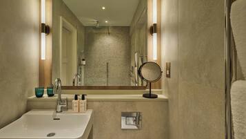 A modern bathroom with a large mirror, a sink, and a shower.
