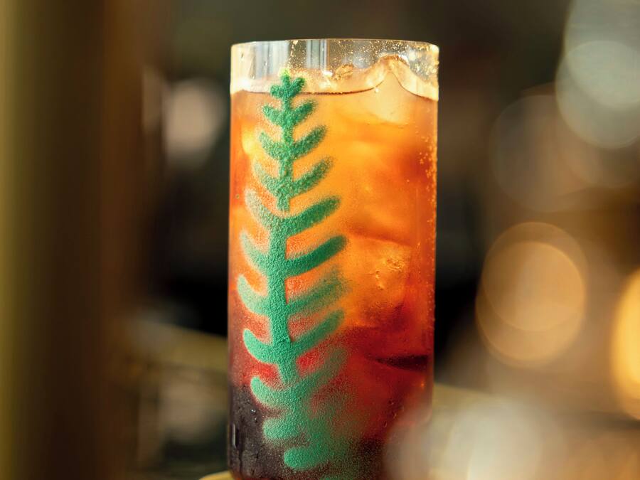 A glass with a green leaf design on a beverage.