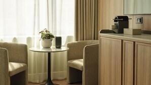 A hotel room with a round table, two chairs, a coffee machine, and a cabinet. - The Imperial (London)