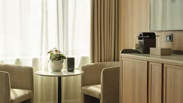 A hotel room with a round table, two chairs, a coffee machine, and a cabinet.