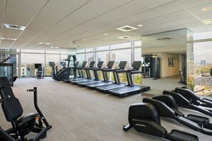 A gym with treadmills, weight machines, and a large window offering a city view. - JW Marriott Atlanta Downtown (Atlanta)