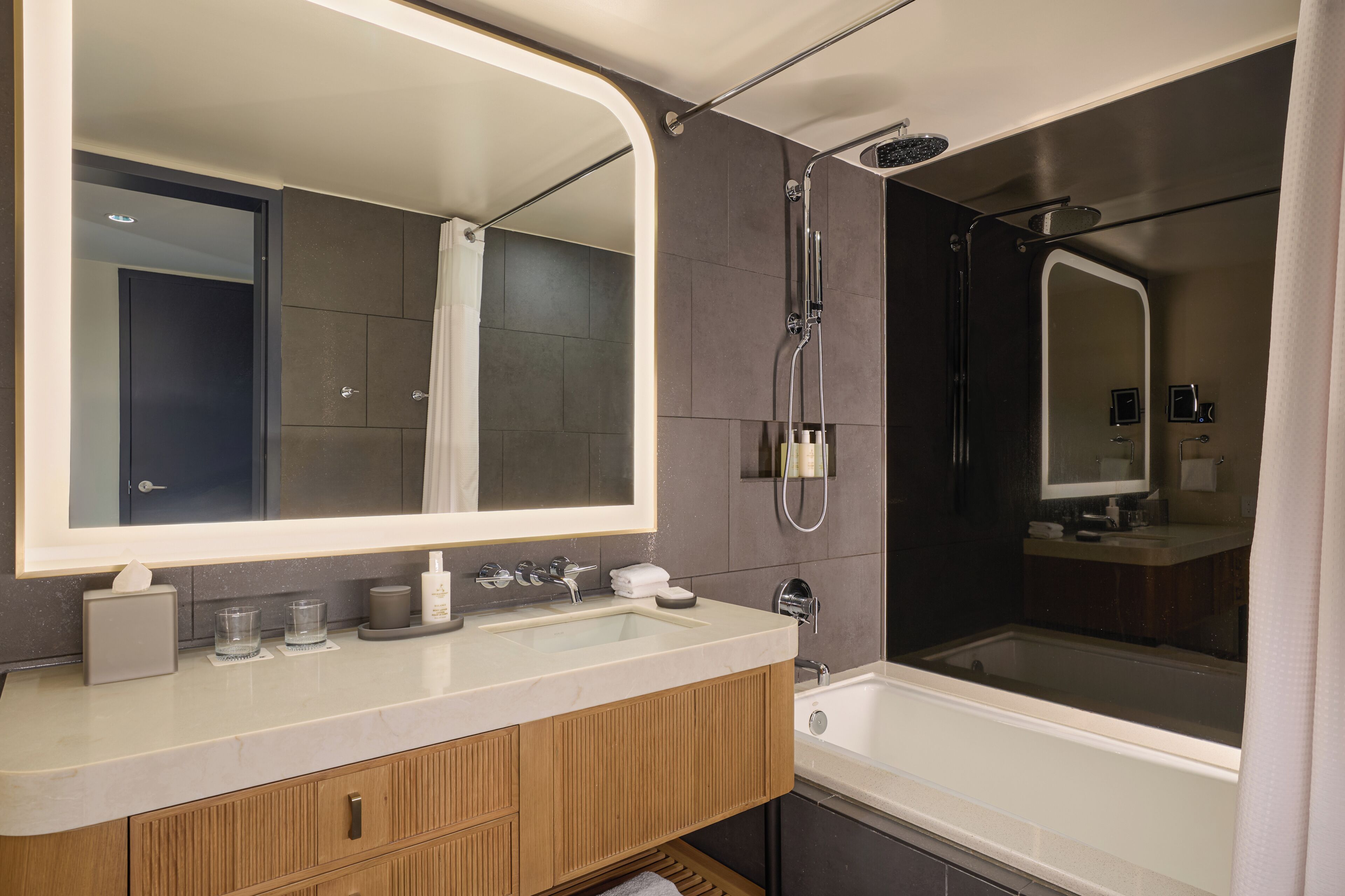 Un baño moderno con un espejo grande, una bañera y una ducha.