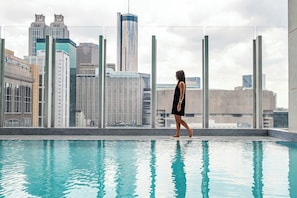 A person walking by a pool with a city skyline in the background. - JW Marriott Atlanta Downtown (Atlanta)