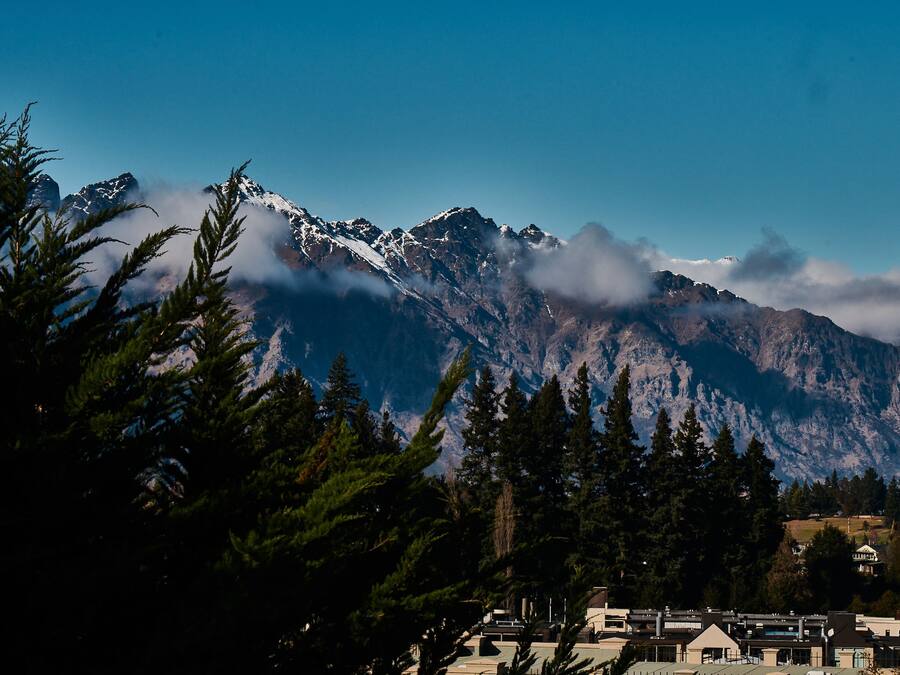 A mountain range with snow-capped peaks and a town in the foreground.