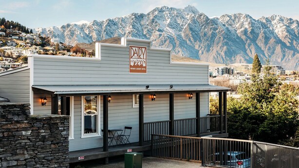 A building with a sign reading "DAIRY THE PRIVATE LIVING HOTEL" with a mountainous backdrop.