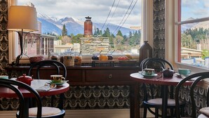 A cozy dining area with a view of mountains, a stone fireplace, and a variety of dishes on the windowsill.