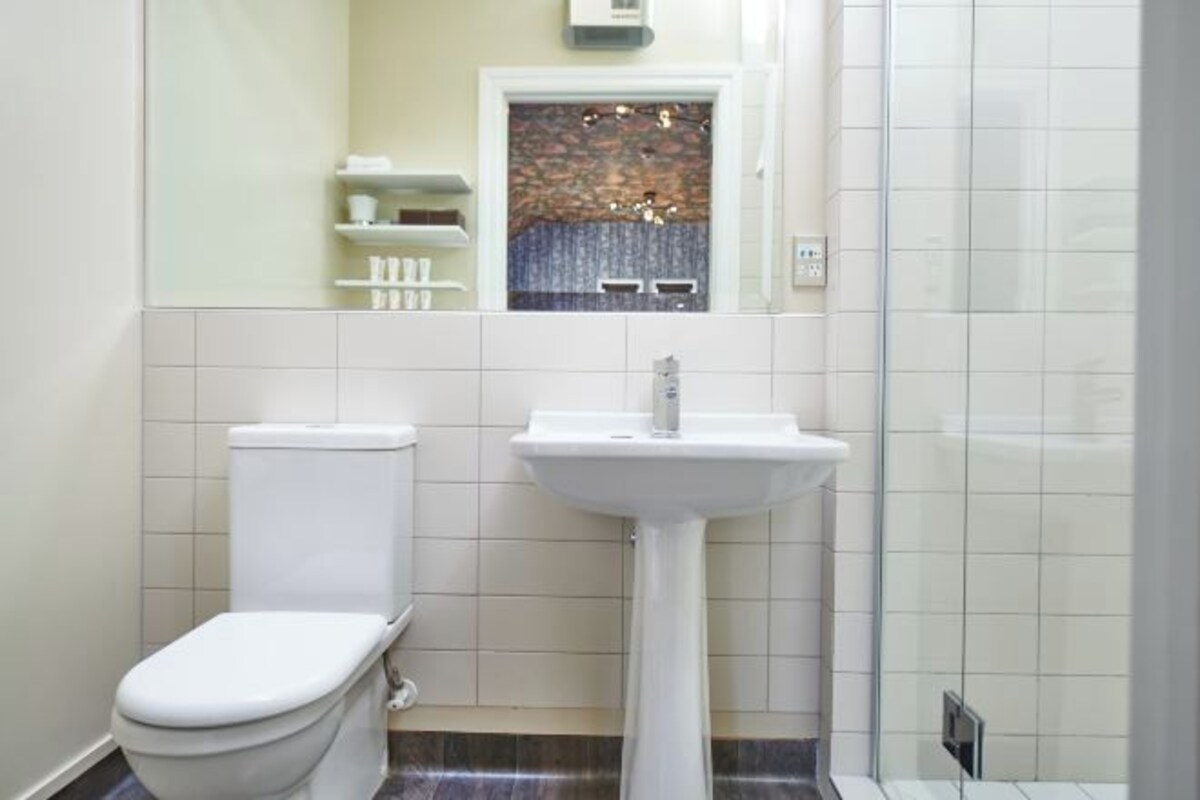 A bathroom with a toilet, sink, and a shower area.