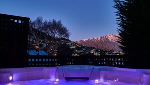 A hot tub with a view of a town and mountains in the background.