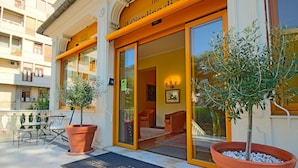 The entrance of a hotel with a welcoming outdoor seating area, a doormat with the hotel's name, and large potted plants. - Il Giardino di Albaro (Genoa)